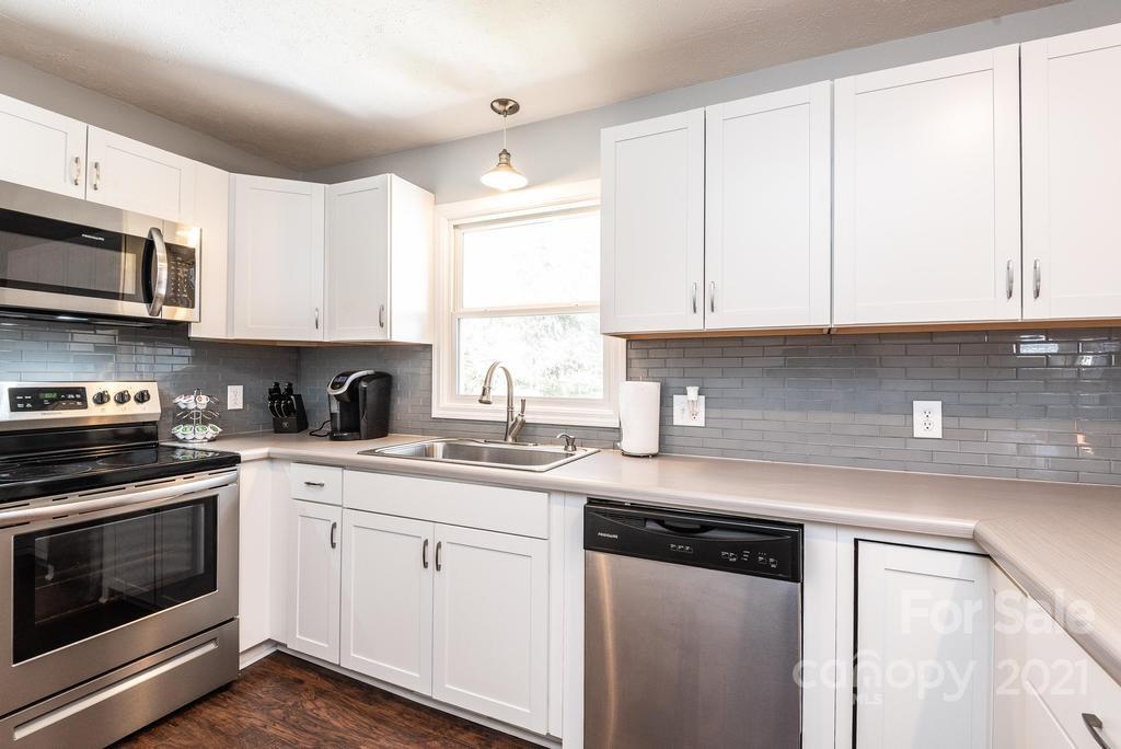 5196 Jenkins Road Morganton, NC 28655 - Photo 19 of 46 a kitchen with stainless steel appliances granite countertop a sink and cabinets with wooden floor