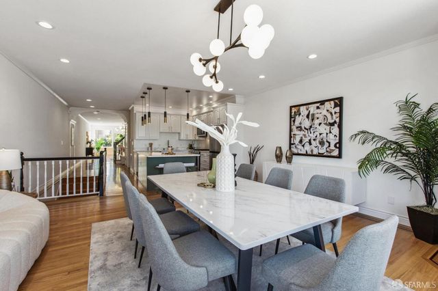 a kitchen with stainless steel appliances granite countertop a sink a stove a refrigerator and a dining table with wooden floor