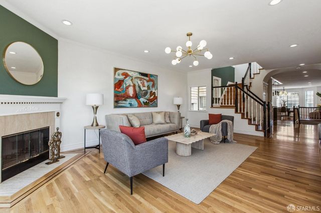 a living room with couches a fireplace and a chandelier
