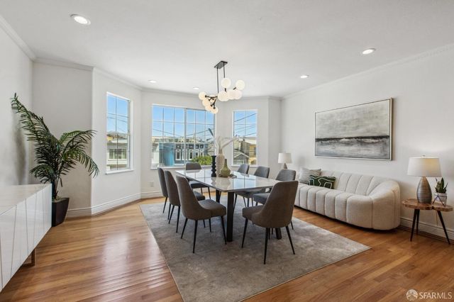 a dining room with wooden floor a chandelier a wooden table and chairs