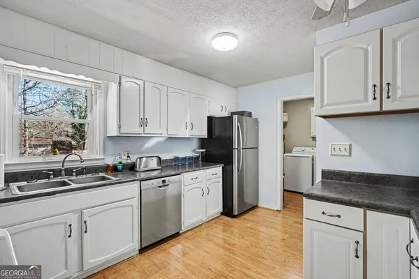 a kitchen with granite countertop a sink cabinets and stainless steel appliances