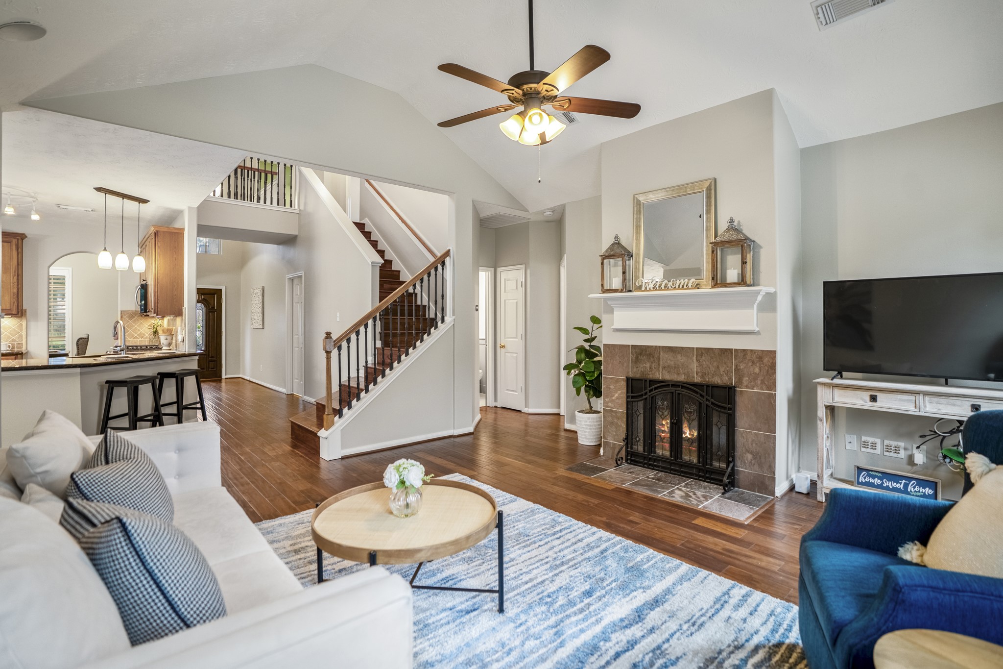 6311 Sparrows Glen Lane Spring, TX 77379 - Photo 14 of 50 Looking back from the living room, the main level feels open and easy to follow—kitchen bar to one side, the front entry and staircase beyond, and the fireplace creating a natural gathering point within the room.