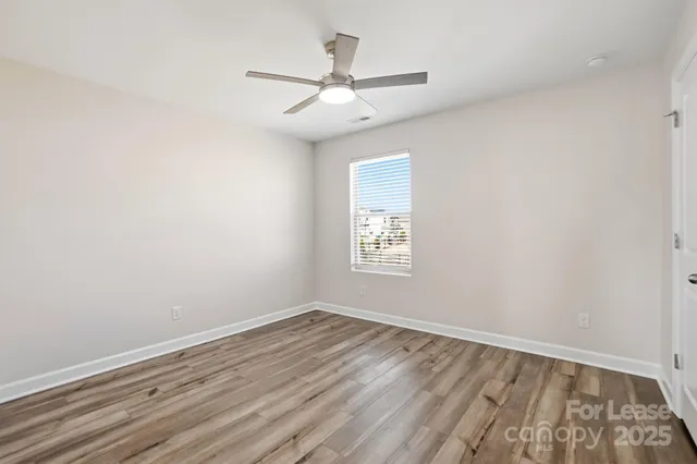 an empty room with a window and ceiling fan