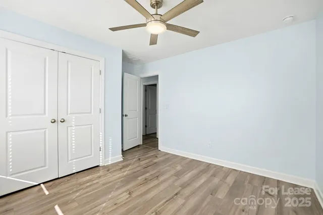an empty room with wooden floor closet and ceiling fan