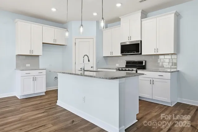 a kitchen with kitchen island granite countertop a sink a counter top space stainless steel appliances and cabinets