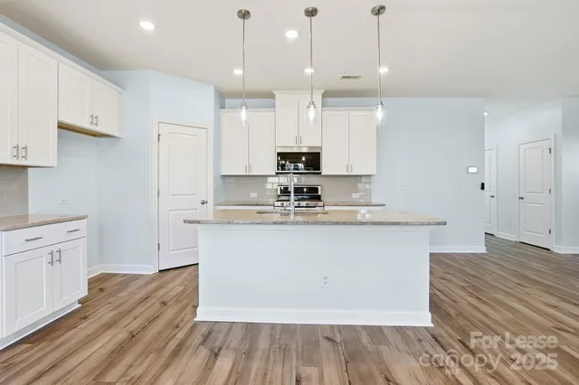 a large kitchen with cabinets wooden floor and stainless steel appliances