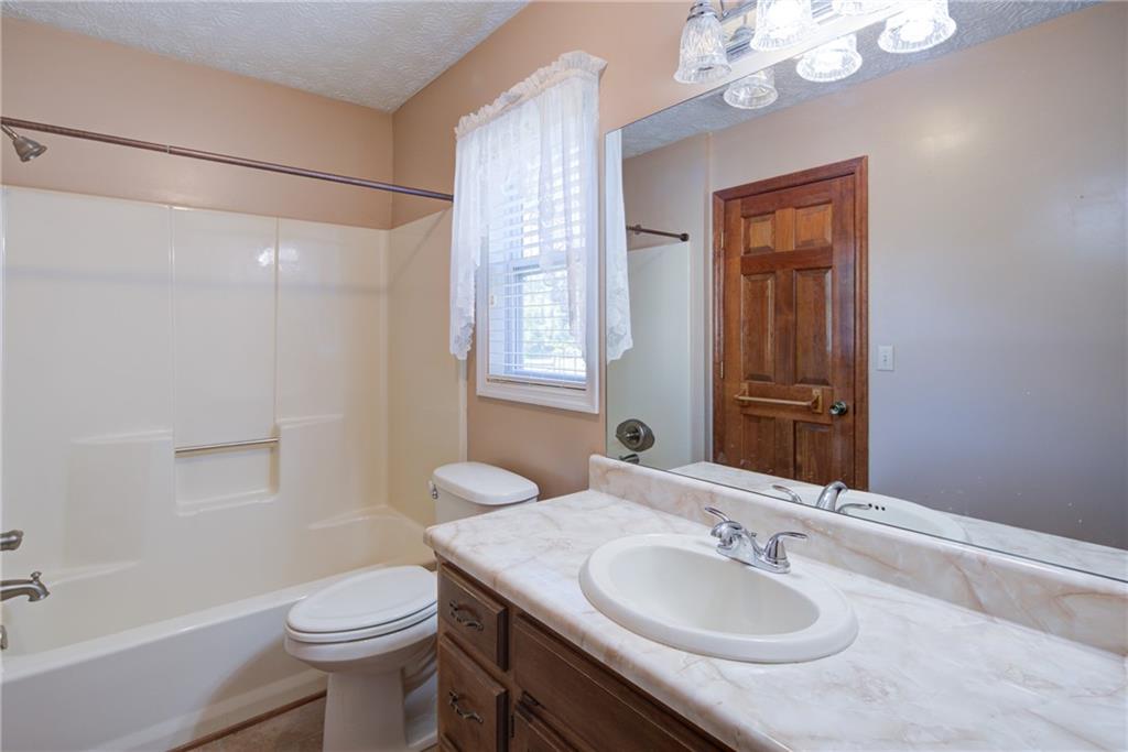 4920 McCoy Circle Cumming, GA 30040 - Photo 13 of 31 a bathroom with a granite countertop sink a toilet a mirror and shower