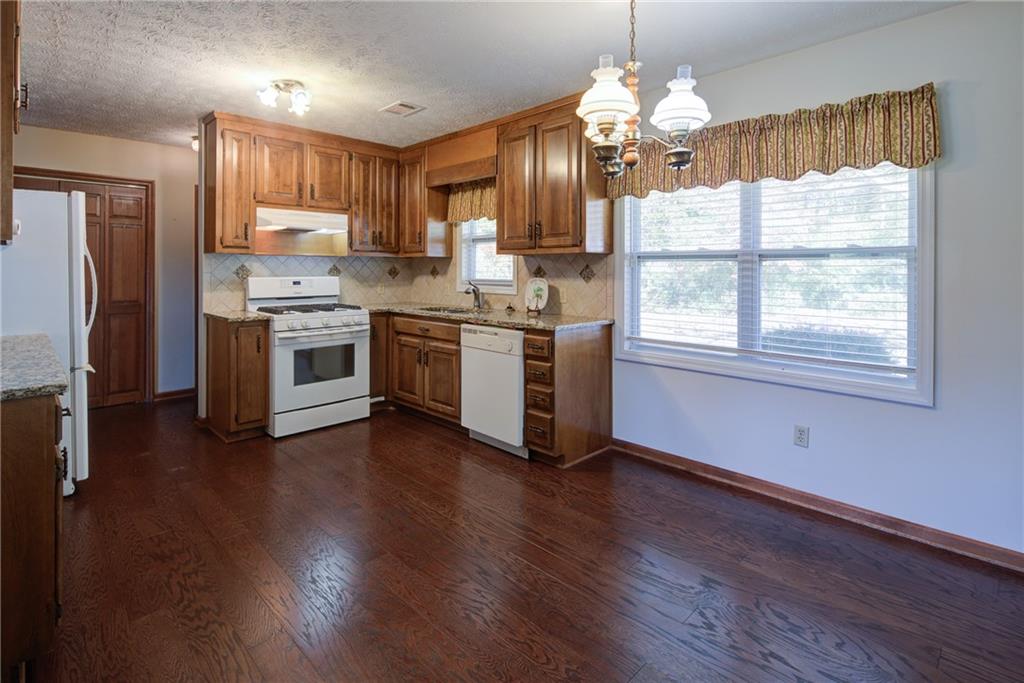 4920 McCoy Circle Cumming, GA 30040 - Photo 2 of 31 a kitchen with stainless steel appliances granite countertop wooden floors and white cabinets