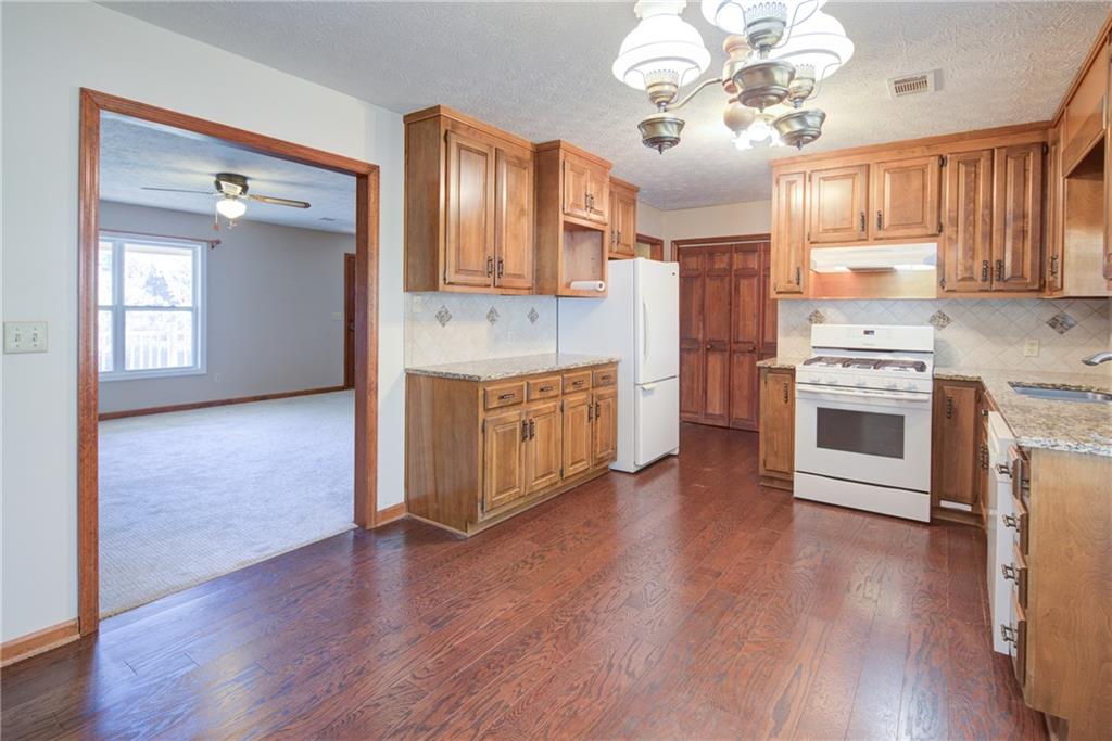4920 McCoy Circle Cumming, GA 30040 - Photo 3 of 31 a kitchen with stainless steel appliances granite countertop a stove top oven a refrigerator a sink and dishwasher with wooden floor