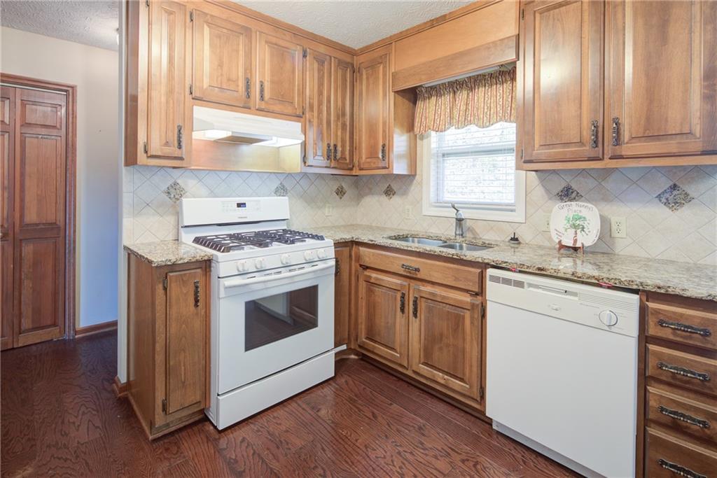 4920 McCoy Circle Cumming, GA 30040 - Photo 5 of 31 a kitchen with granite countertop wooden cabinets and white appliances