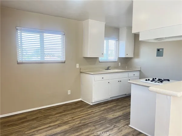 a room with a stove a sink wooden floor and cabinets