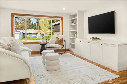 a living room with furniture a flat screen tv and floor to ceiling window