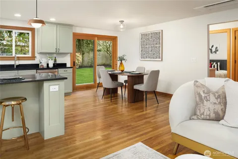 a living room with stainless steel appliances granite countertop furniture wooden floor and a window