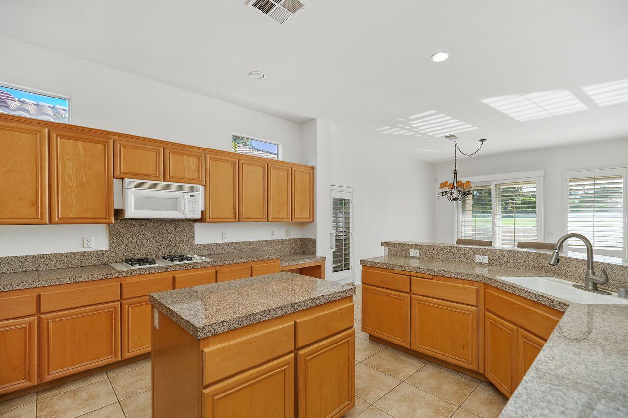 75715 Heritage West Palm Desert, CA 92211 - Photo 12 of 51 a kitchen with kitchen island granite countertop a sink a counter space appliances and cabinets