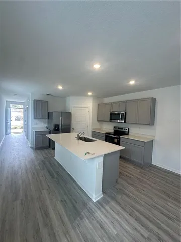 a large kitchen with a large counter top a sink stainless steel appliances and cabinets