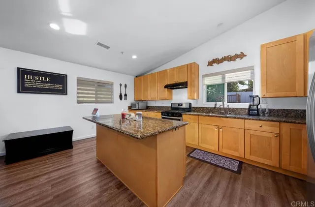 a kitchen with stainless steel appliances granite countertop a sink stove and wooden floor