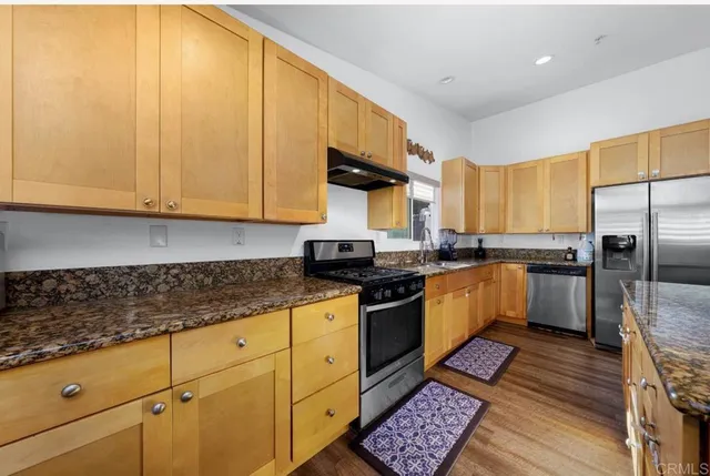 a kitchen with stainless steel appliances granite countertop a sink a stove and refrigerator