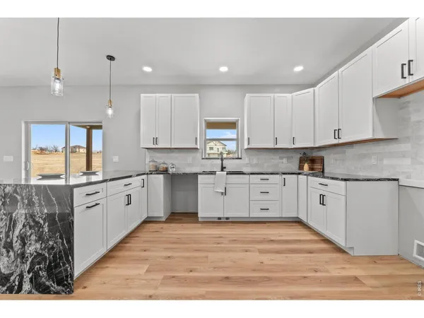 a large kitchen with granite countertop a white stove top oven and white cabinets