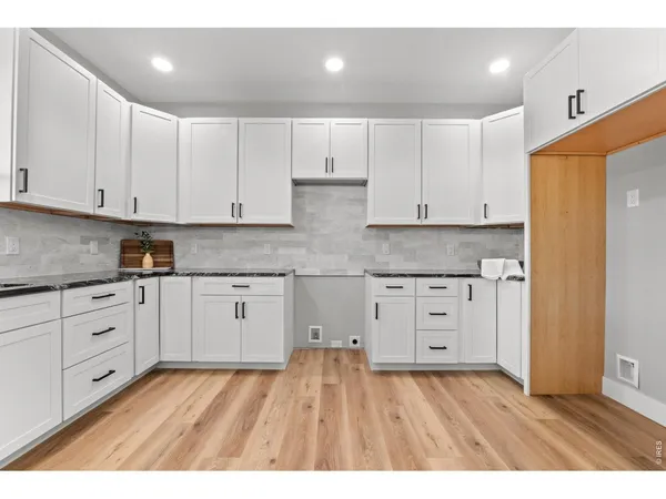 a kitchen with granite countertop white cabinets and white appliances