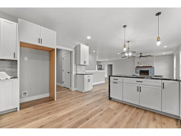 a open kitchen with white cabinets and wooden floor