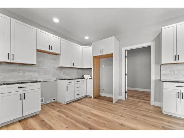 a kitchen with granite countertop white cabinets and stainless steel appliances