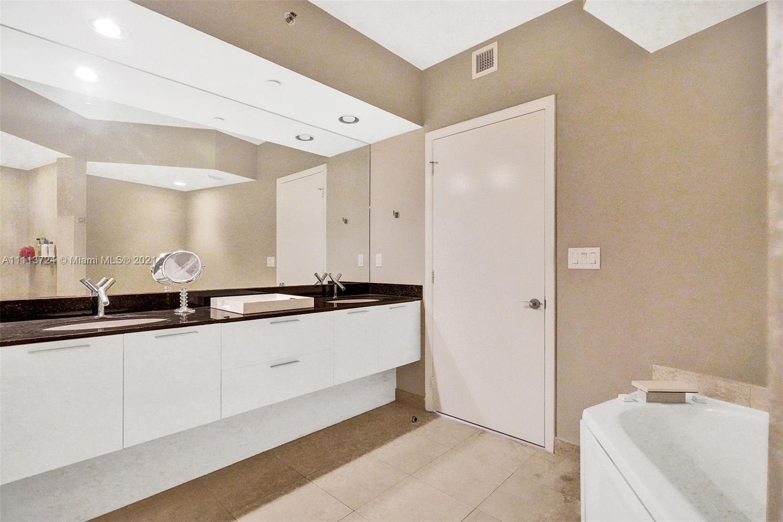 400 Alton Road, Unit 1011 Miami Beach, FL 33139 - Photo 12 of 27 a large white bathroom with a large mirror and a sink