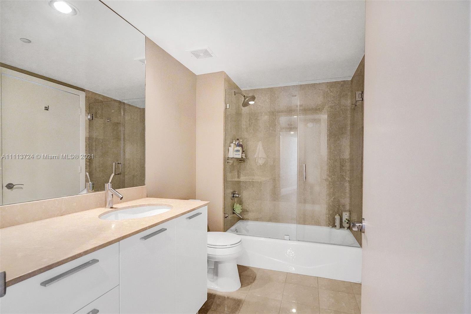 400 Alton Road, Unit 1011 Miami Beach, FL 33139 - Photo 17 of 27 a bathroom with a granite countertop sink toilet a shower and a bathtub