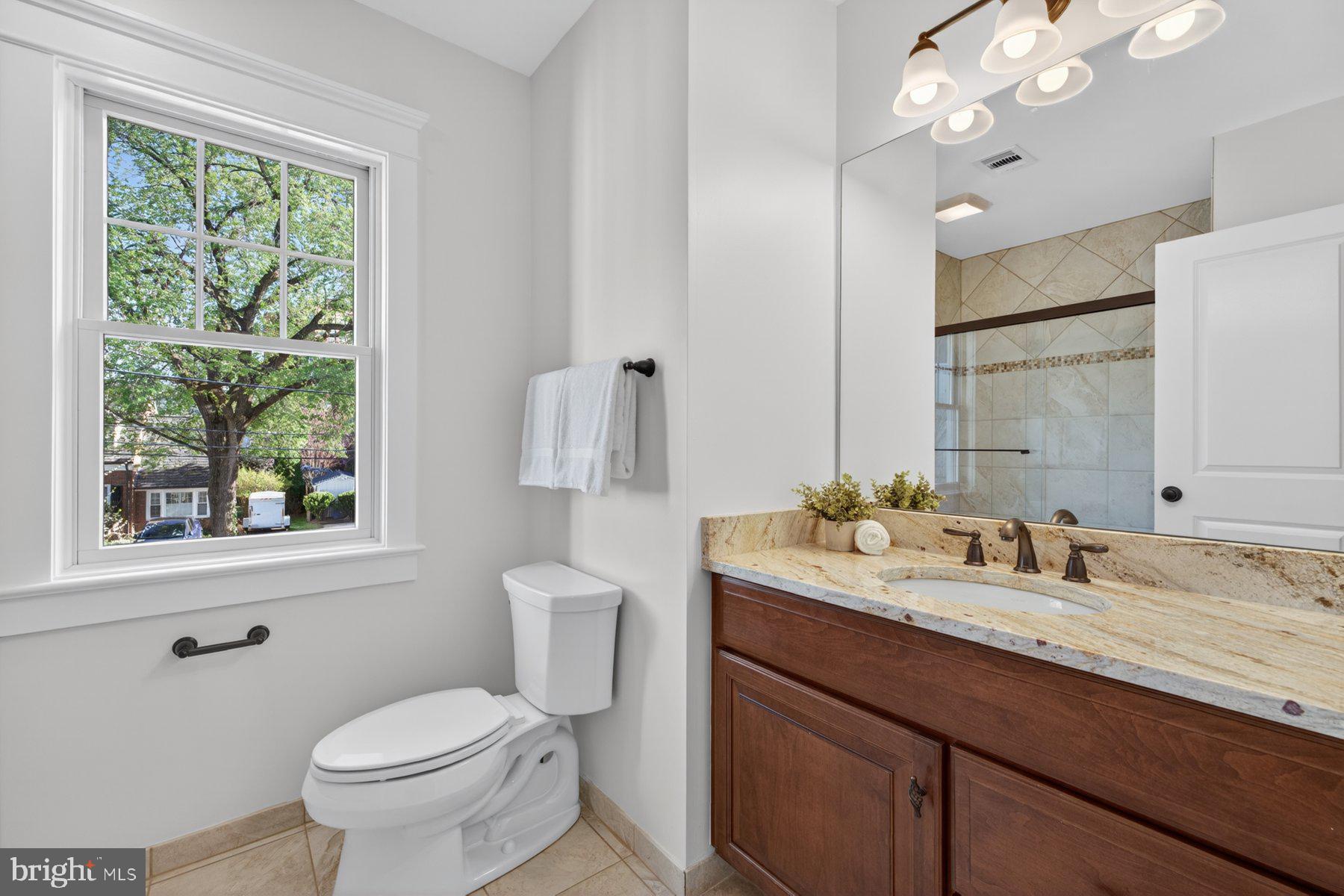 5011 Rugby Avenue Bethesda, MD 20814 - Photo 30 of 65 a bathroom with a granite countertop toilet a sink a large mirror and a window