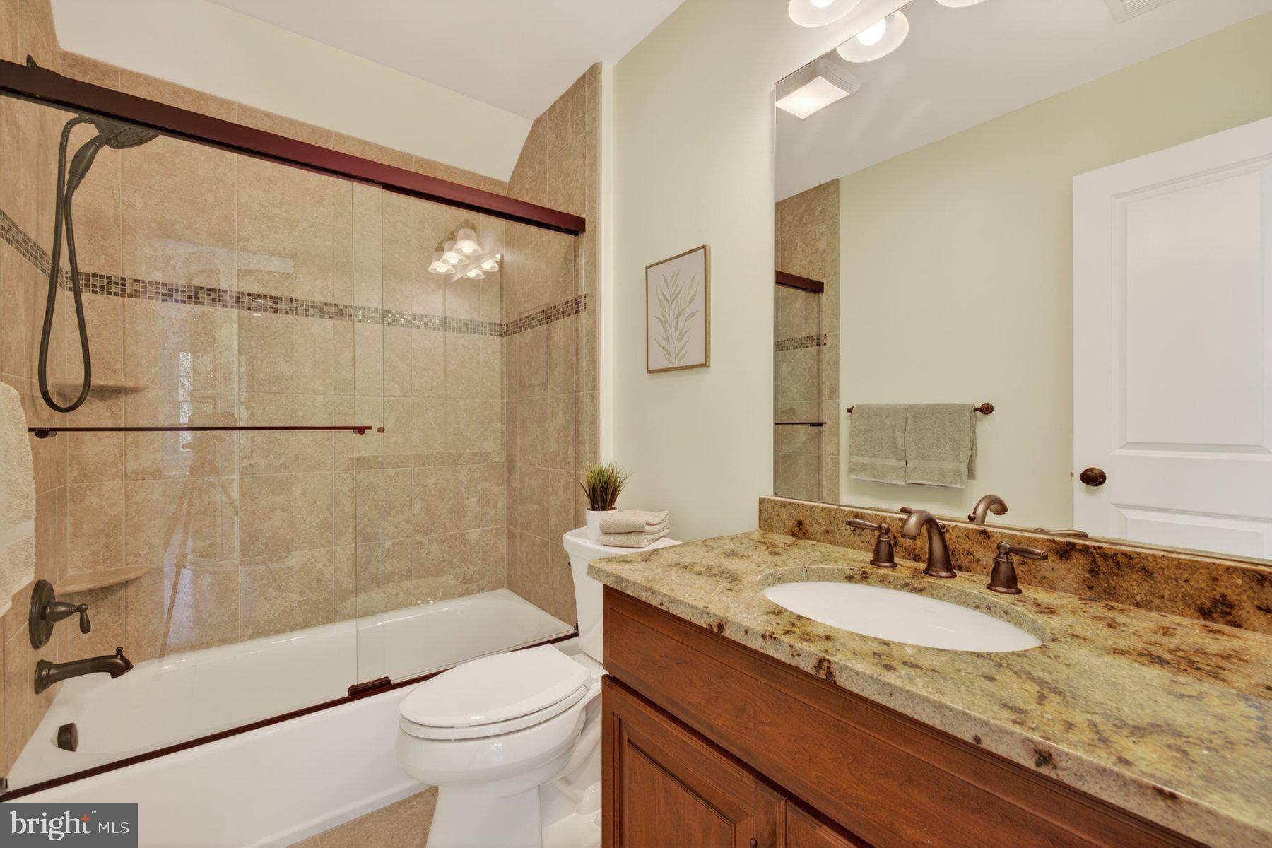 5011 Rugby Avenue Bethesda, MD 20814 - Photo 42 of 65 a bathroom with a granite countertop sink a toilet and shower
