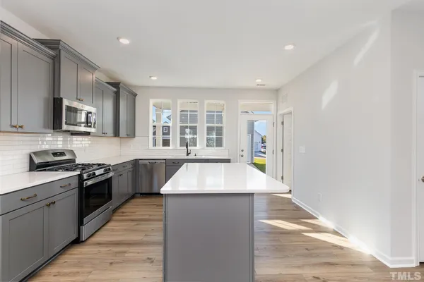 a large kitchen with stainless steel appliances granite countertop a sink and a stove top oven