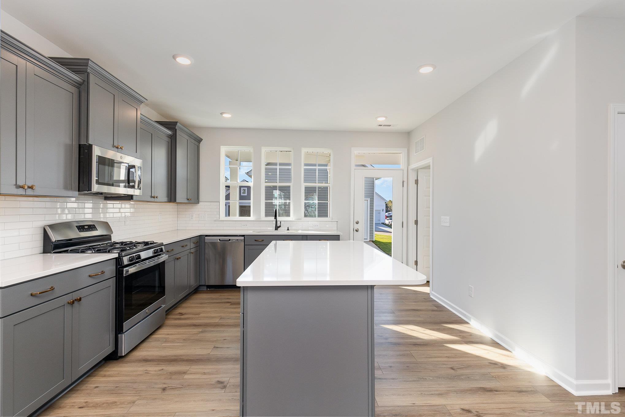 271 Pear Blossom Parkway Clayton, NC 27520 - Photo 9 of 25 a large kitchen with stainless steel appliances granite countertop a sink and a stove top oven