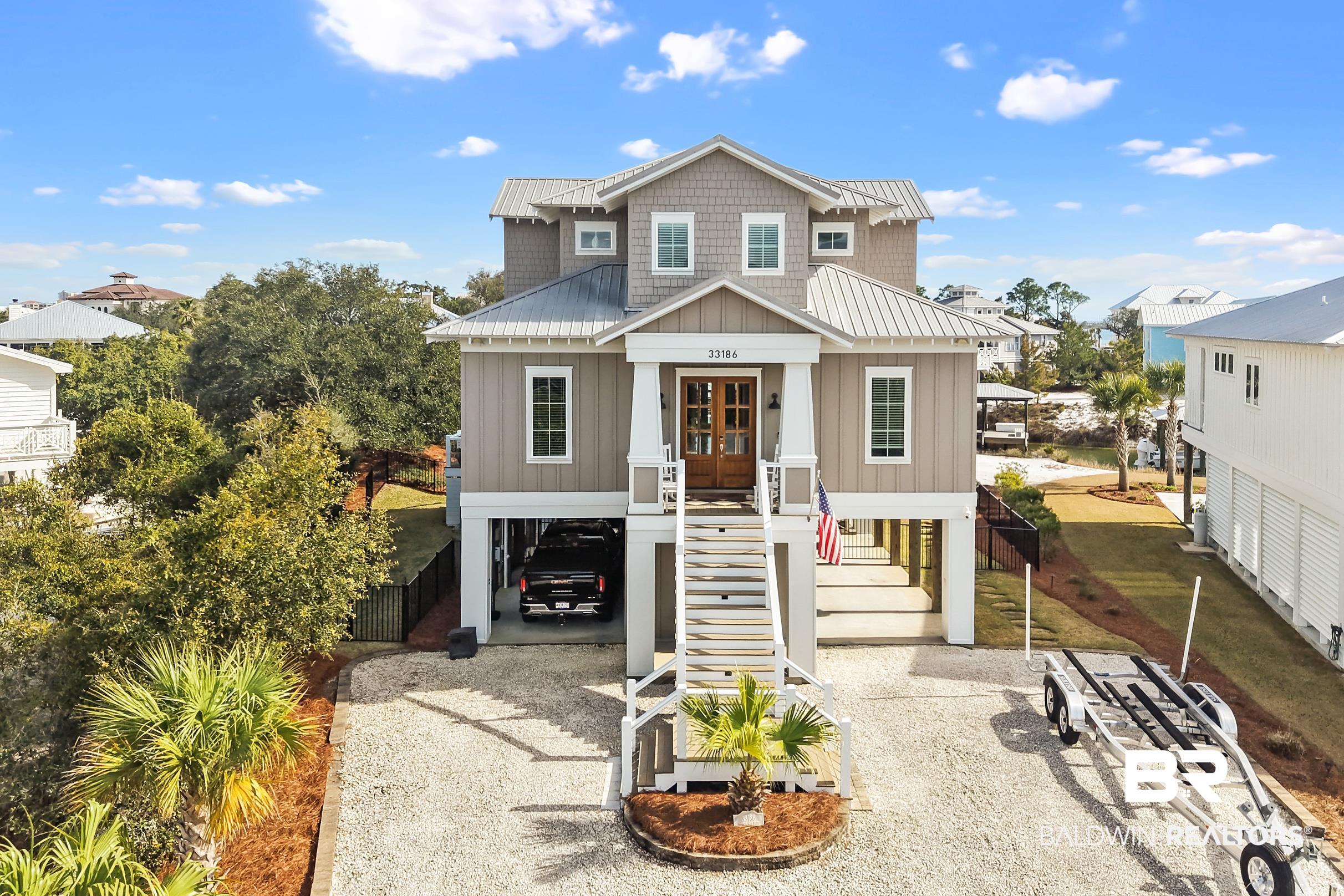 33186 Marlin Key Drive Orange Beach, AL 36561 - Photo 2 of 87 Raised beach house featuring a carport, board and batten siding, gravel driveway, a metal roof, and french doors