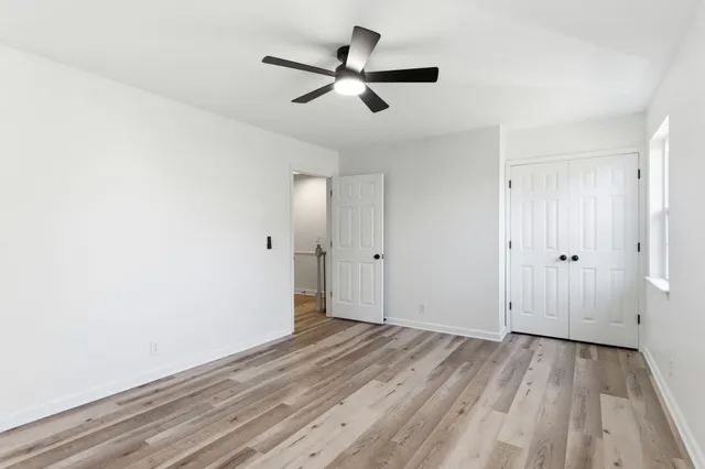 an empty room with wooden floor and a ceiling fan