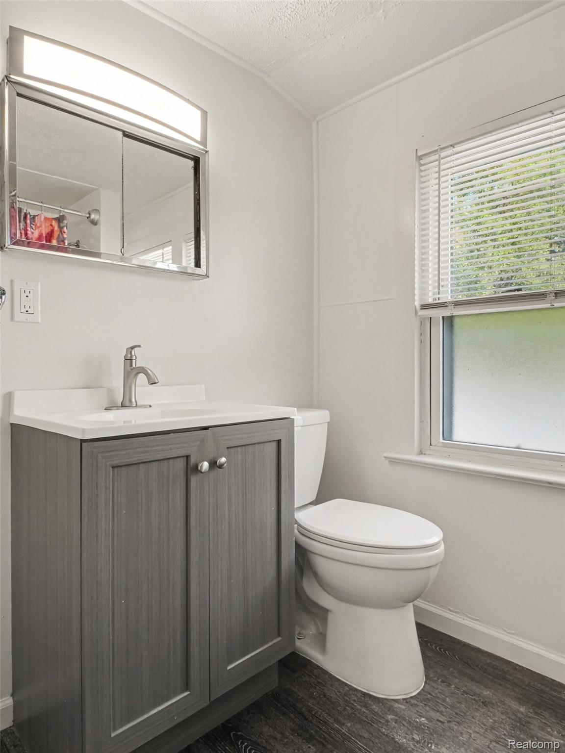 2840 Miller Road Flint, MI 48503 - Photo 31 of 49 Vanity with a white countertop and brushed nickel faucet, wood-finish flooring, and a medicine cabinet with integrated lighting