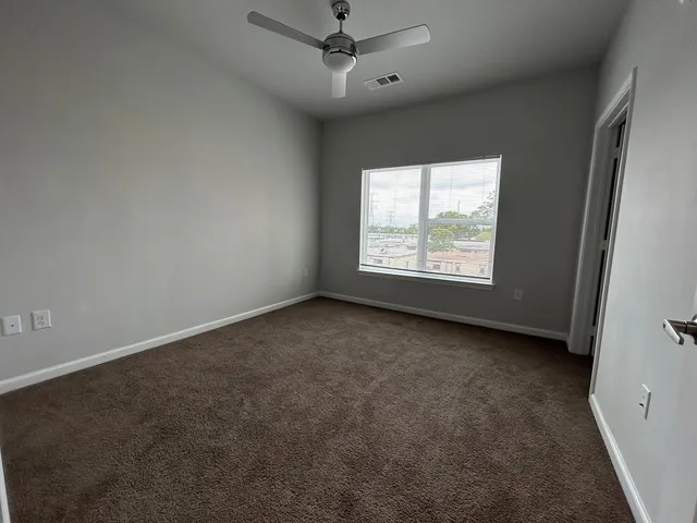 an empty room with a window and a fan