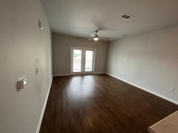 an empty room with wooden floor and windows