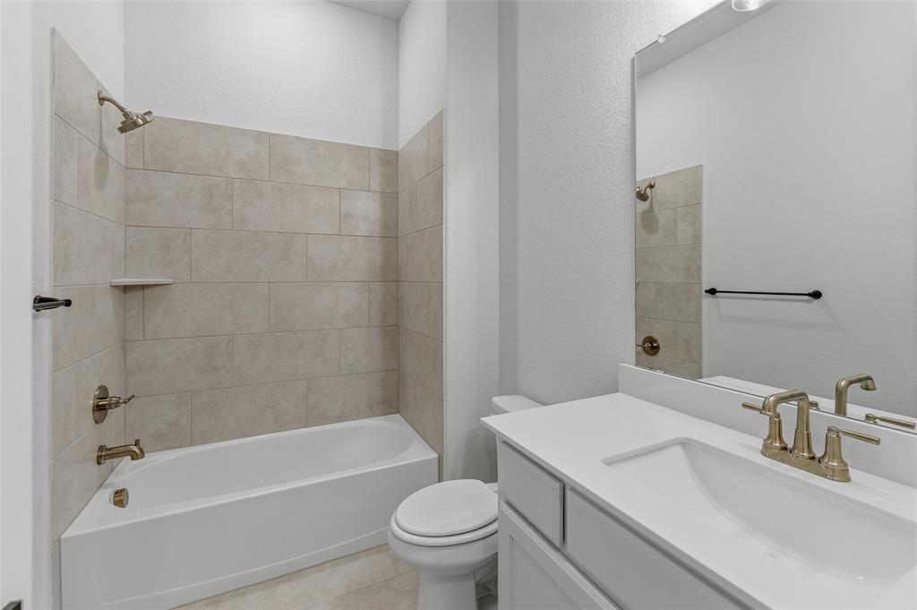 2208 Continent Court Krum, TX 76249 - Photo 8 of 26 Bathroom featuring a built-in tub with tile surround, a single vanity with an integrated sink, a rectangular mirror, and bronze-finish fixtures