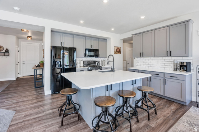 252 North Sunrise Rnch Drive Mapleton, UT 84664 - Photo 18 of 62 Modern kitchen featuring an expansive island with a white countertop, gray cabinetry, subway tile backsplash, and wood-finish flooring