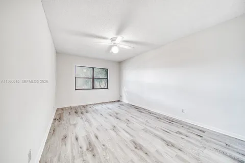 an empty room with windows and ceiling fan