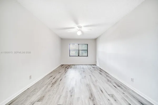 an empty room with wooden floor ceiling fan and windows