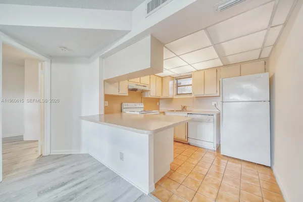 a kitchen with a sink a refrigerator white cabinets and wooden floor