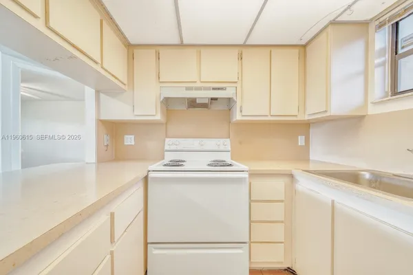 a kitchen with kitchen island a stove a sink and white cabinets with wooden floors