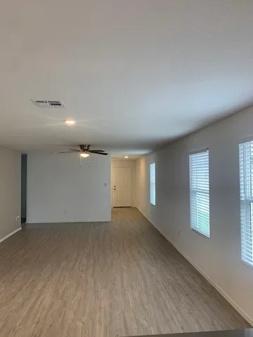en empty room with wooden floor and windows