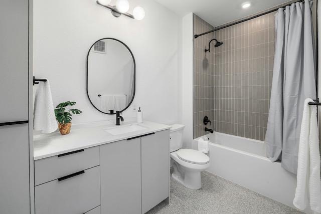 1701 Simond Avenue, Unit 615 Austin, TX 78723 - Photo 13 of 25 Bathroom featuring a light gray vanity with a white countertop and integrated sink, an oval-framed mirror, and a shower-over-tub with vertical gray tile surround and black fixtures
