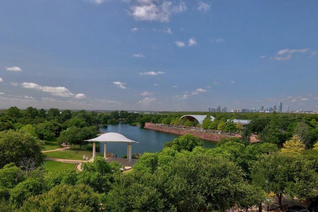 1701 Simond Avenue, Unit 615 Austin, TX 78723 - Photo 14 of 25 Expansive verdant landscape featuring a body of water, a modern white gazebo, and a distant city skyline