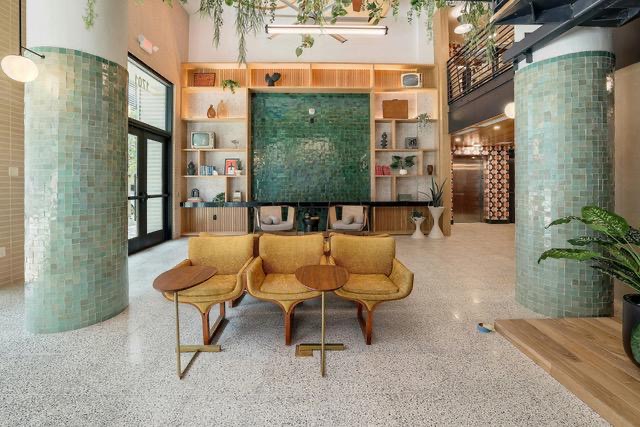 1701 Simond Avenue, Unit 615 Austin, TX 78723 - Photo 18 of 25 Expansive communal lounge with terrazzo flooring, two tiled support columns, and a full-height built-in shelving unit