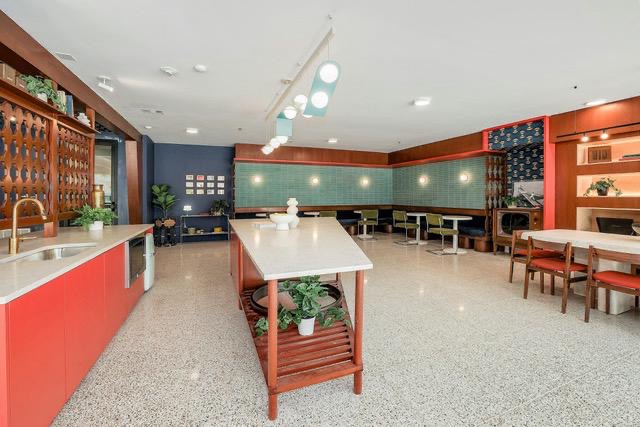 1701 Simond Avenue, Unit 615 Austin, TX 78723 - Photo 20 of 25 Spacious common area featuring terrazzo flooring, a red cabinetry kitchen with integrated sink, a large center island, built-in shelving, and booth seating