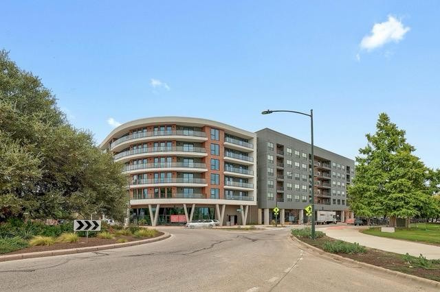 1701 Simond Avenue, Unit 615 Austin, TX 78723 - Photo 3 of 25 Modern multi-story building featuring a curved facade, individual balconies with glass railings, and a ground-floor retail presence