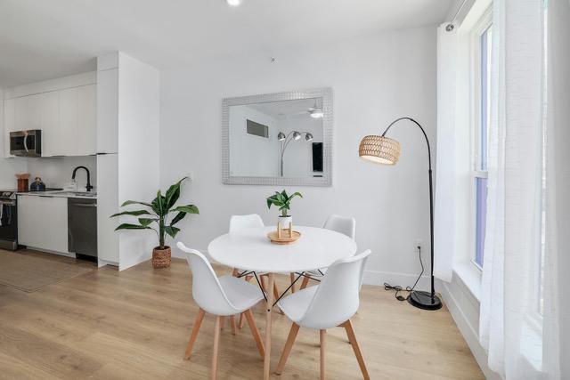 1701 Simond Avenue, Unit 615 Austin, TX 78723 - Photo 7 of 25 Open-concept living space featuring wood-finish flooring, a contemporary kitchen with white cabinetry and stainless steel appliances, and a floor-to-ceiling window