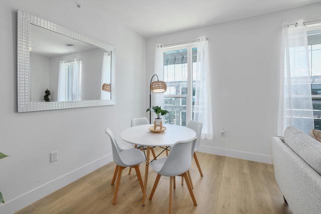1701 Simond Avenue, Unit 615 Austin, TX 78723 - Photo 8 of 25 Dining area featuring light wood-finish flooring, white walls, and a large window with sheer curtains